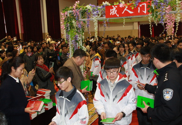 同学们通过成人门,接收领导递上的《宪法》和《成人纪念册》